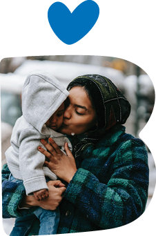 A caregiver holding and kissing a child.