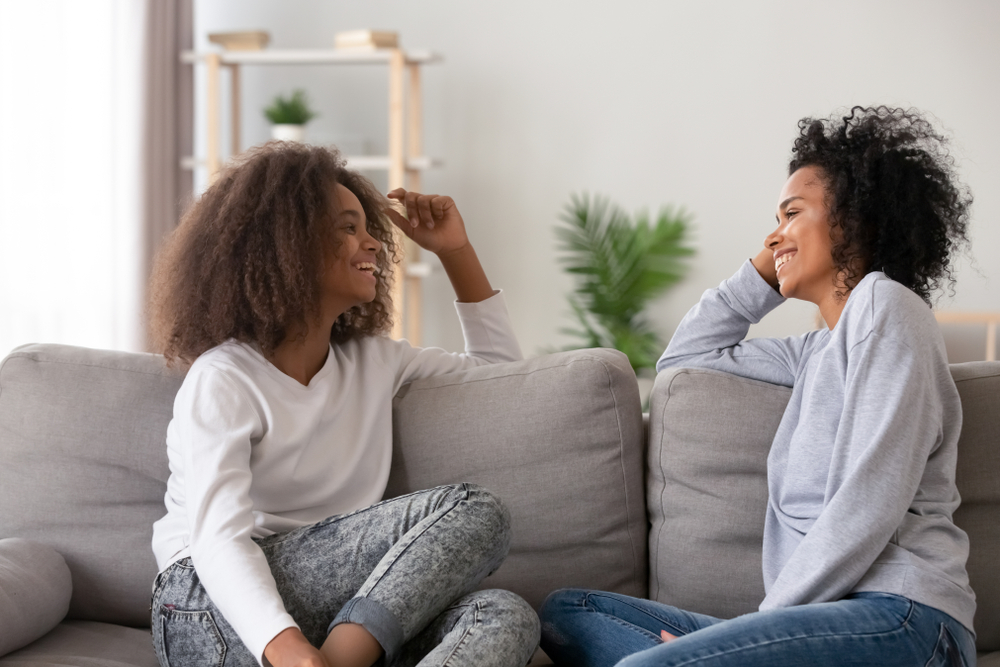 Mother and teen daughter talking on couch.