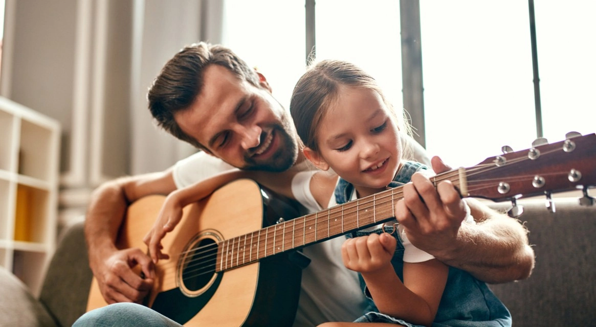 A parent playing guitar with her dad